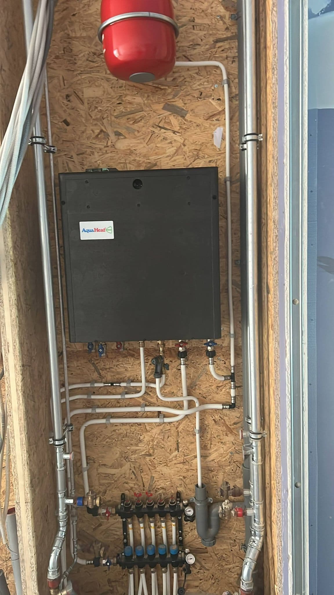 AquaHeat afgiftesysteem met rood expansievat en verdeler voor vloerverwarmingsgroepen