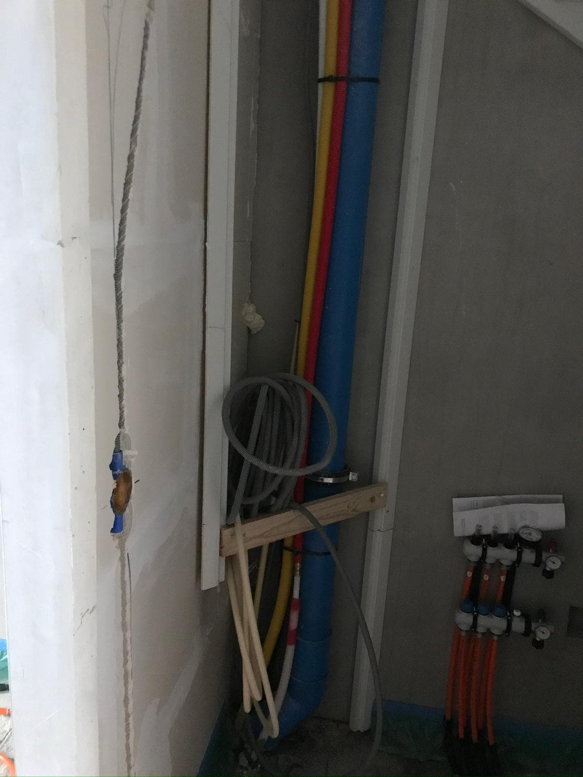 Leidingwerk met blauwe, gele en rode stijgleidingen in wandschacht