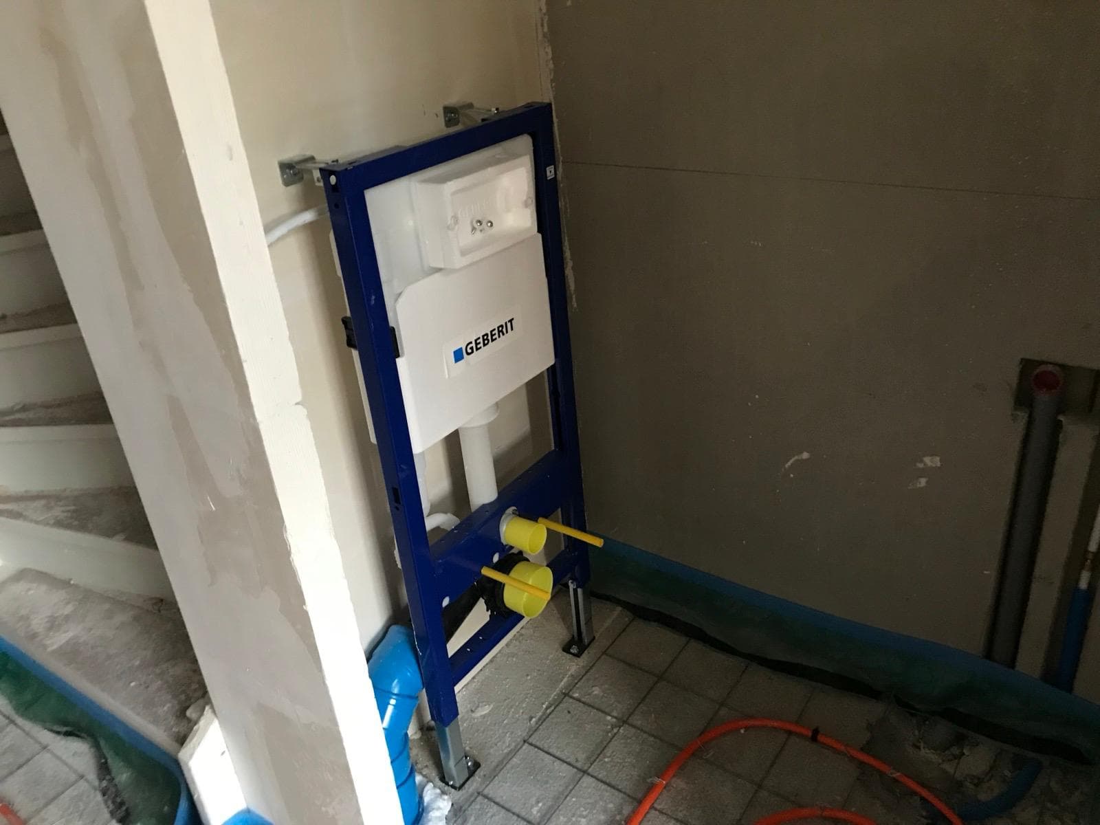Geberit inbouwreservoir frame geplaatst tegen wand met gele aansluitpunten