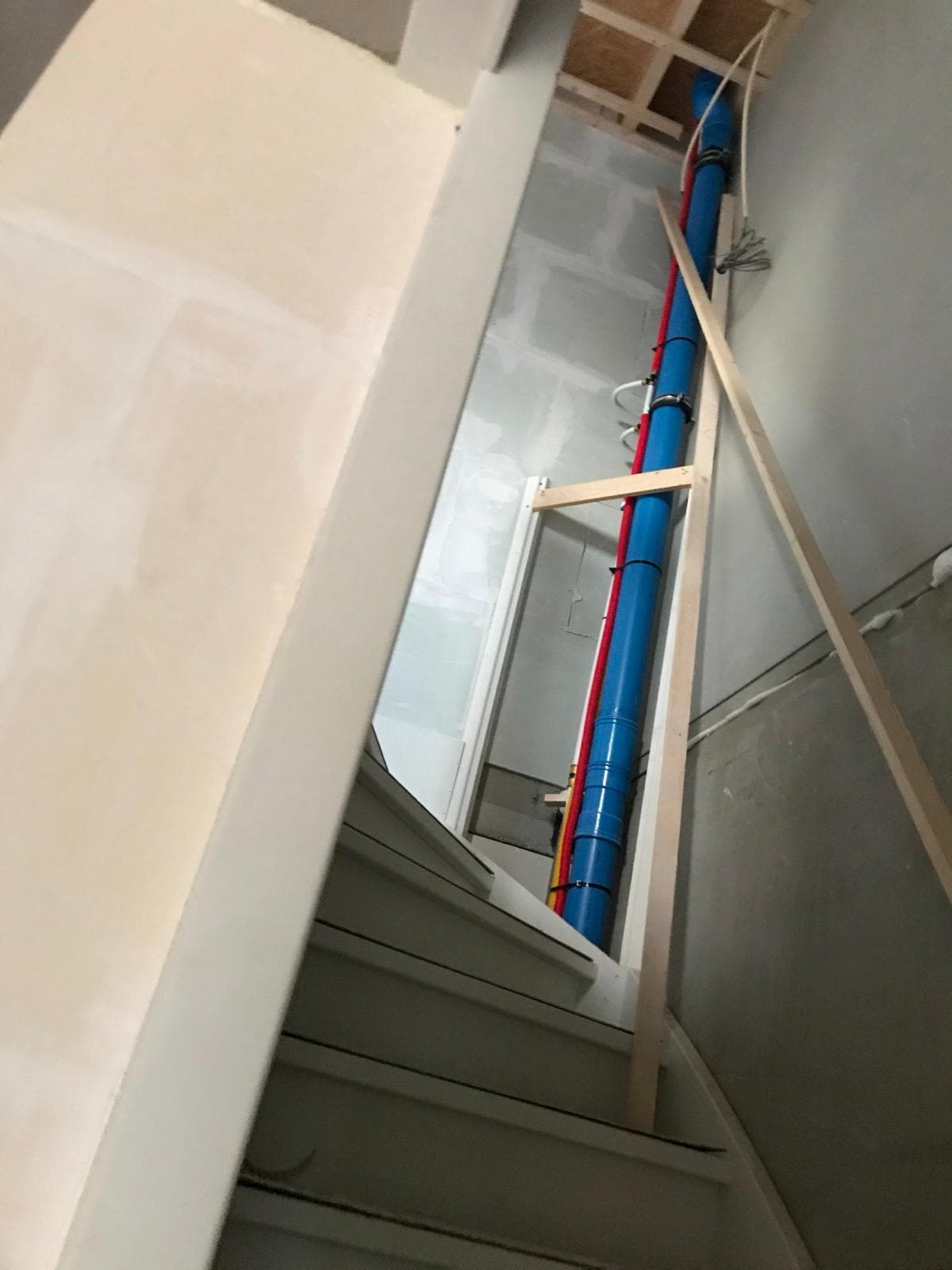 Stijgleiding met rode en blauwe isolatie netjes weggewerkt in trappenhuis
