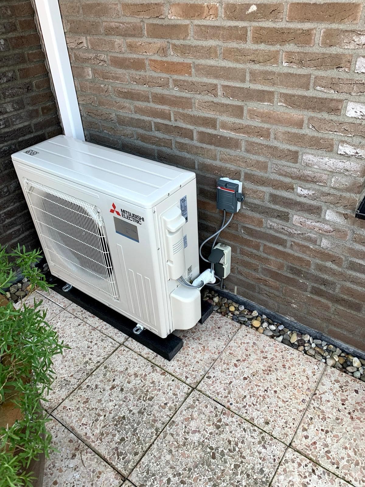 Buitenunit warmtepomp met wandcontactdoos en nette leidingdoorvoer
